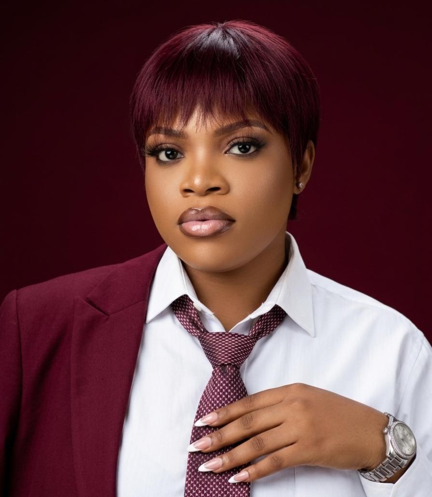 A portrait of a woman with a chic short maroon pixie cut wig styled at Mibest Beauty in Aba